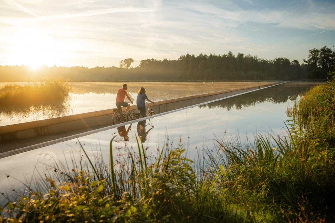 Twee personen fietsen door het water in Bokrijk.