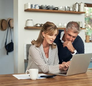 Koppel analyseert op de laptop de mogelijkheden van een levensverzekering in de context van de meerwaardebelasting.