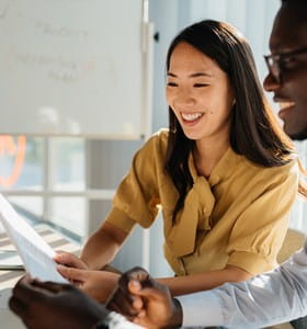 Twee collega’s bekijken samen een document op een laptop, om bij arbeidsongeschiktheid van de bedrijfsleider de continuïteit van de activiteit te garanderen.