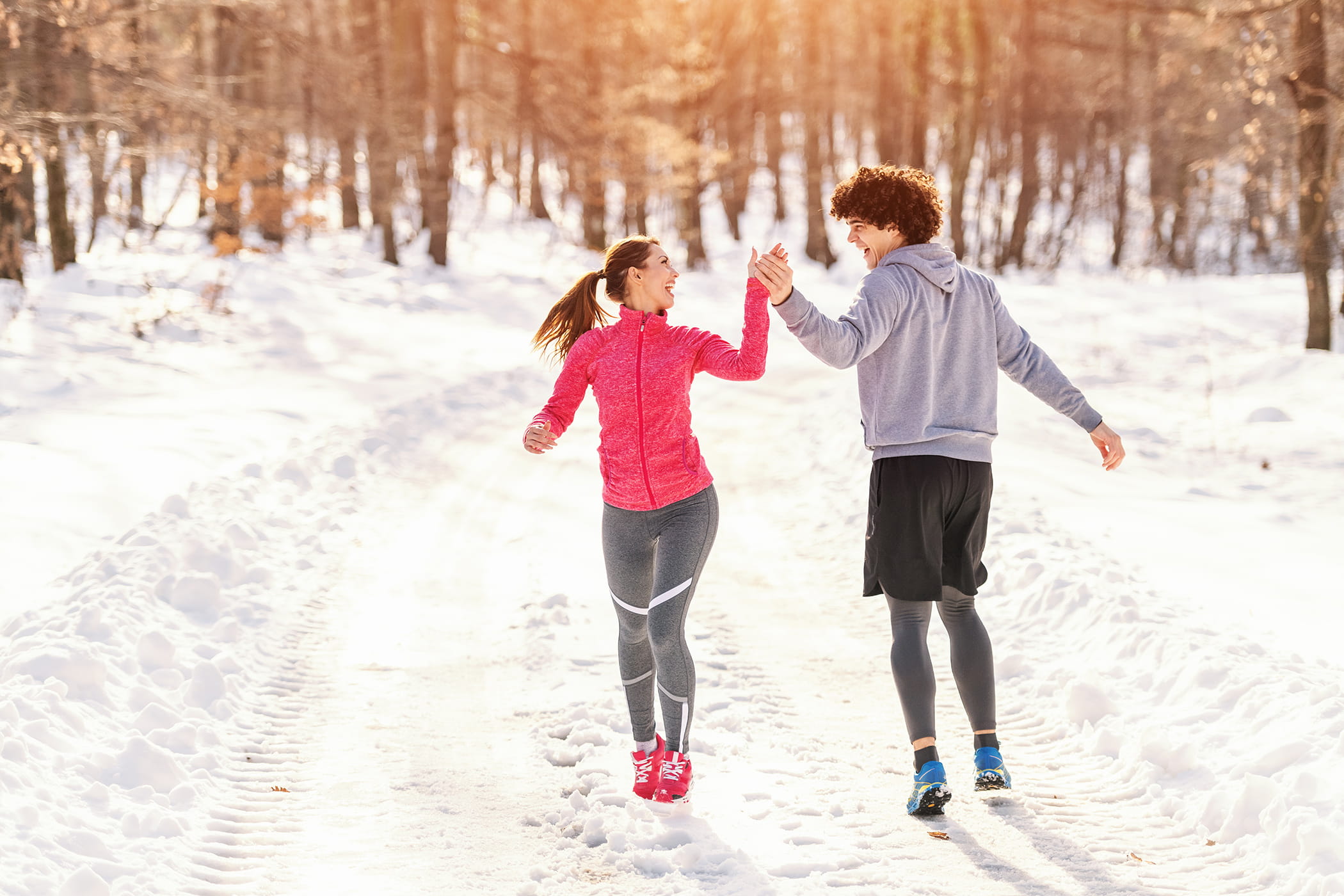 Twee jonge mensen genieten van de sneeuw in de winter en zorgen zo voor een gezonde levensstijl. 
