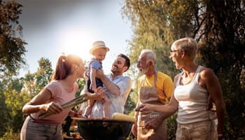 Une famille avec grands-parents, enfants et petits-enfants autour d'un barbecue convivial