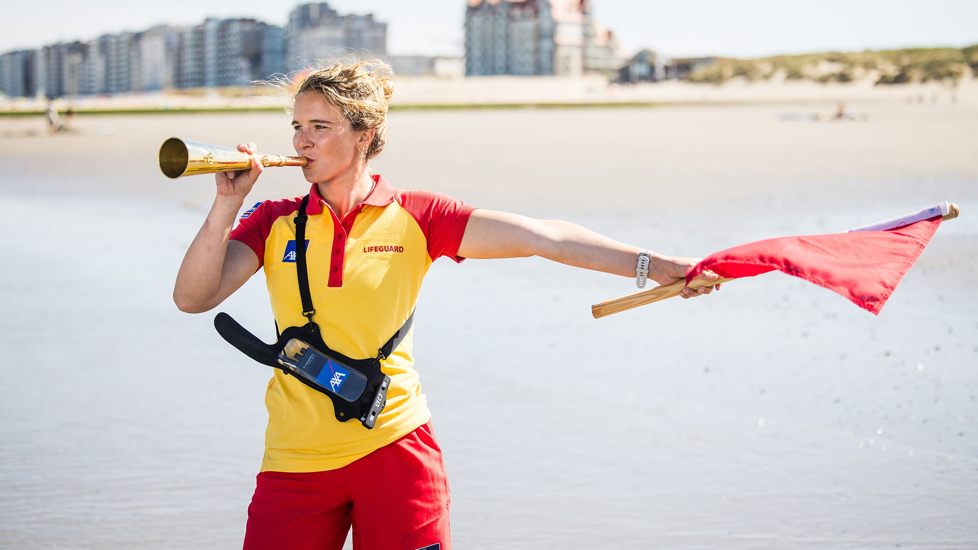 Un Lifeguard sur la côte belge agite le drapeau rouge pour prévenir les accidents.