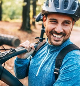 Homme portant un casque de vélo, qui se rend à vélo au travail et bénéficie d’une réduction sur son assurance Auto.