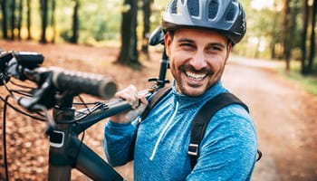 Man met fietshelm lacht omdat hij een autoverzekering per kilometer heeft.