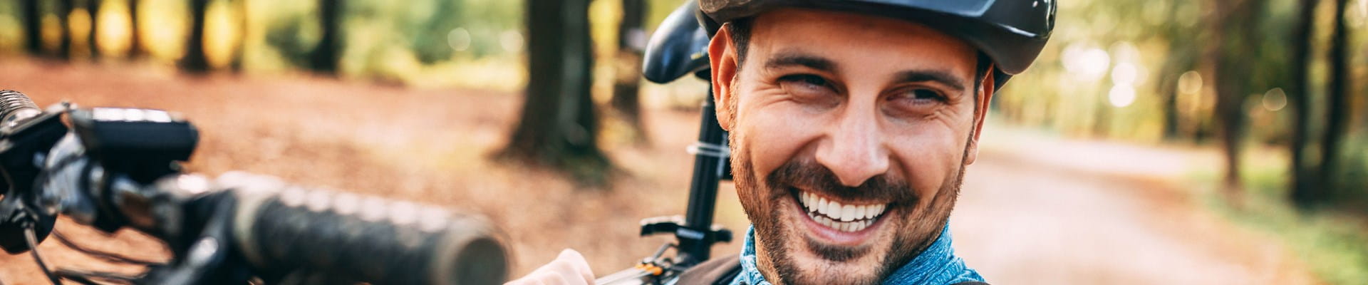 Man met fietshelm lacht omdat hij een autoverzekering per kilometer heeft.