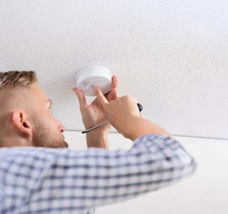 Propriétaire qui vérifie le bon fonctionnement de son détecteur de fumée.