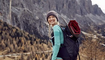 Vrouw gaat wandelen in de bergen nadat ze de reisverzekeringen heeft vergeleken.