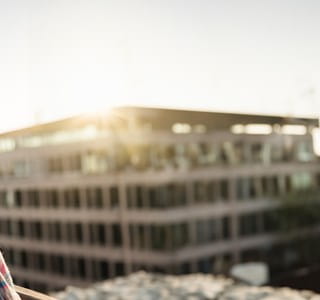 Une dame âgée bénéficie de sa pension complémentaire et regarde les appartements depuis son balcon.