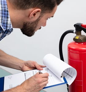 Homme qui vérifie son exctincteur pour une prévention des incendies optimale.