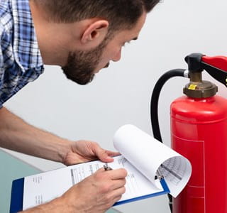 Homme qui vérifie son exctincteur pour une prévention des incendies optimale.