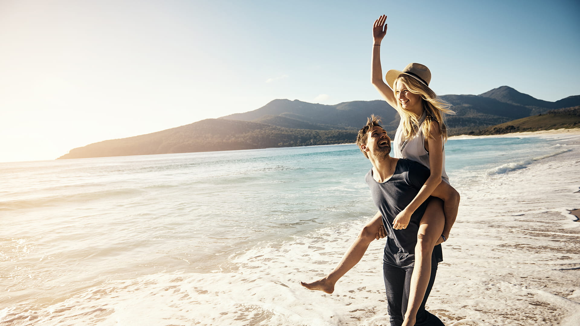 Jeune couple profitant d’une balade sur la plage, en toute sérénité avec une assurance voyage.