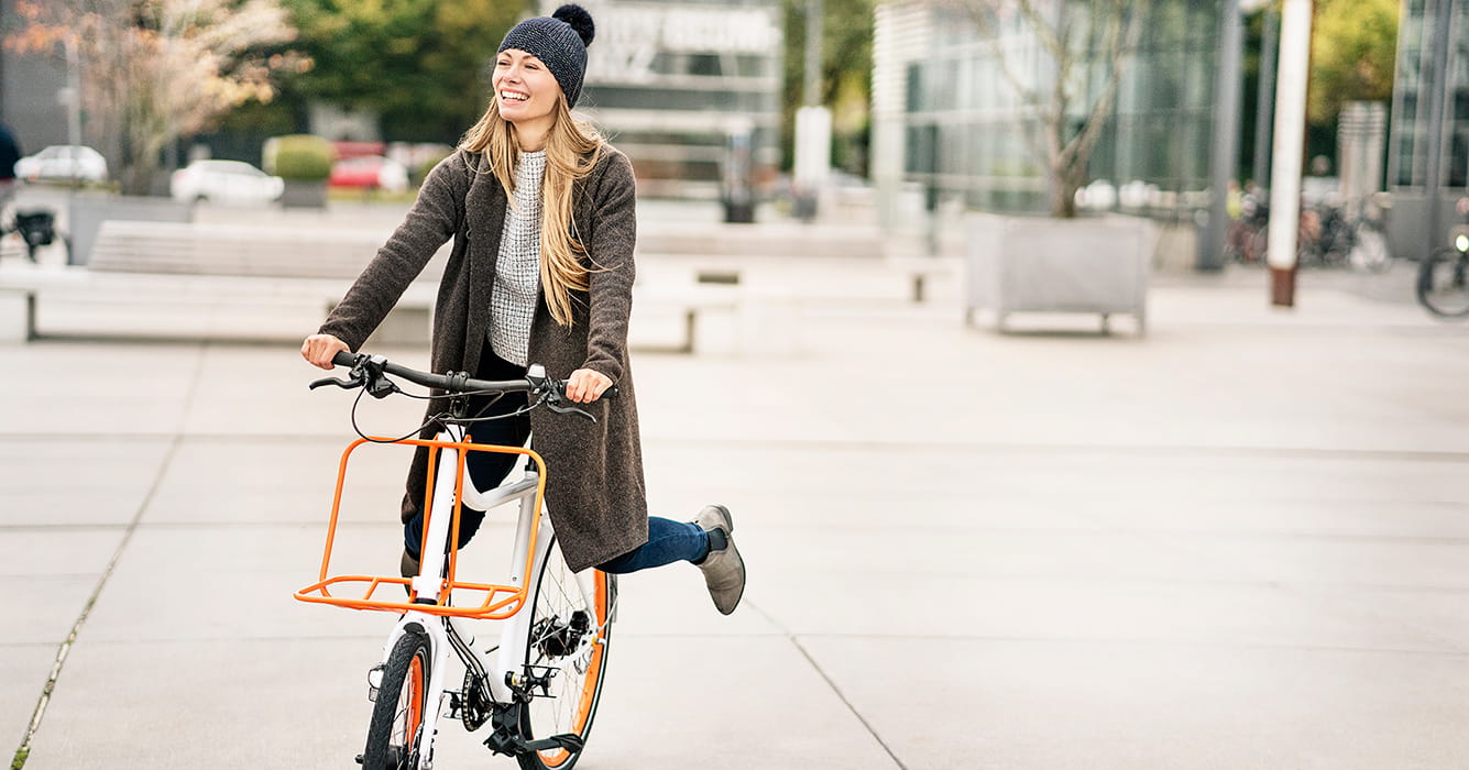 Jonge vrouw op een fiets, beschermd bij schade aan anderen dankzij haar Familiale verzekering.
